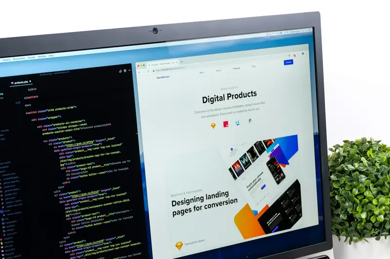 Code and a web design on a screen, with a phone and tablet beside it
