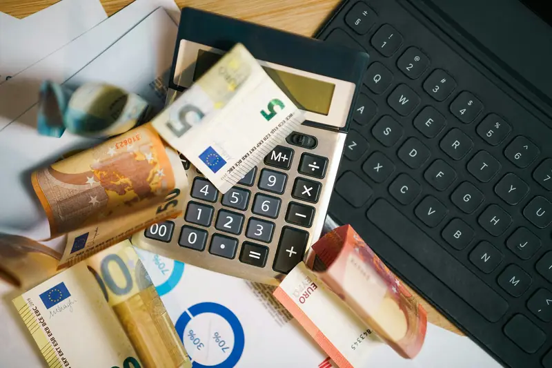 Euro notes, a calculator and a keyboard on a desk