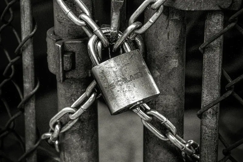 A padlock on a chain around a gate, in black and white