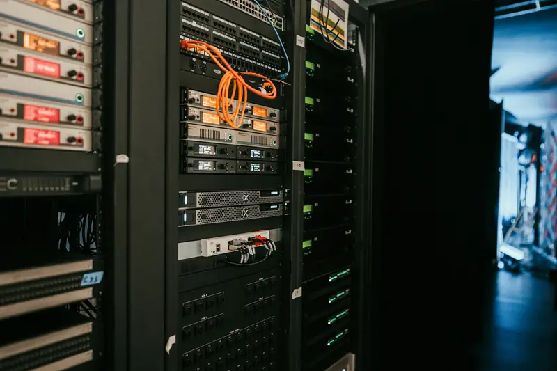 Black racks with servers and network equipment, with an orange cable at the top