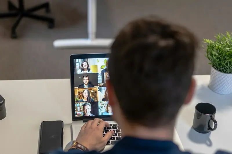 Someone on a video call with a group of colleagues on a laptop