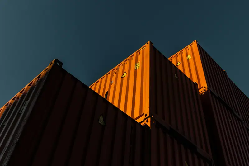 Orange shipping containers seen from below against a dark sky