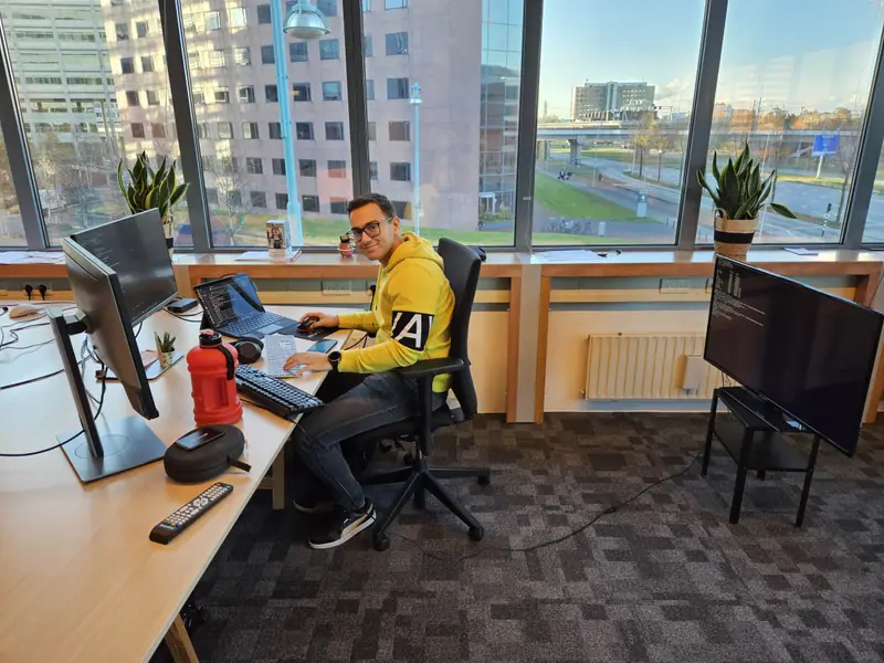 A developer at his desk, with two screens and a view over the city