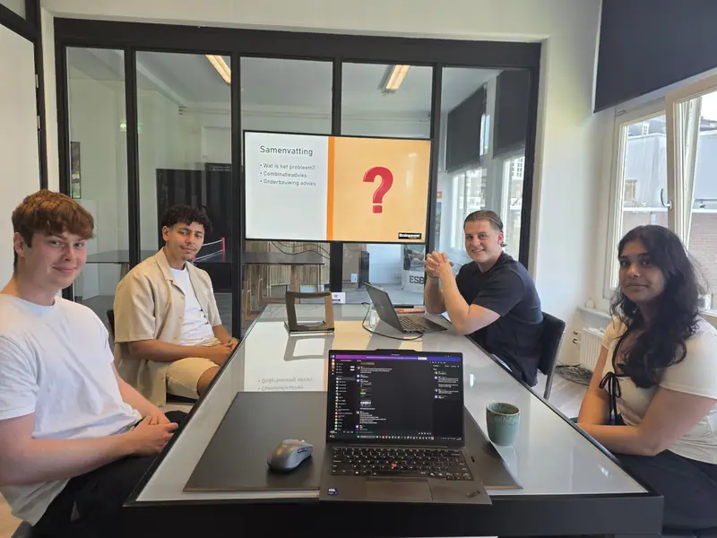 Das Team an einem Tisch mit Laptops während einer Arbeitssitzung